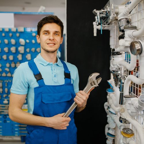 Plumber with pipe wrenches poses at the showcase, plumbering store choice. Man buying sanitary engineering tools and equipment in shop
